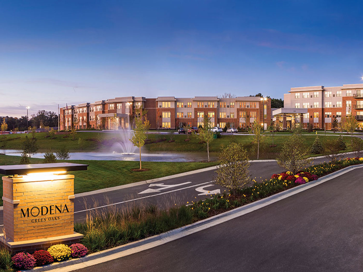 Evening View Of Modena Green Oaks Building And Pond With Fountain.