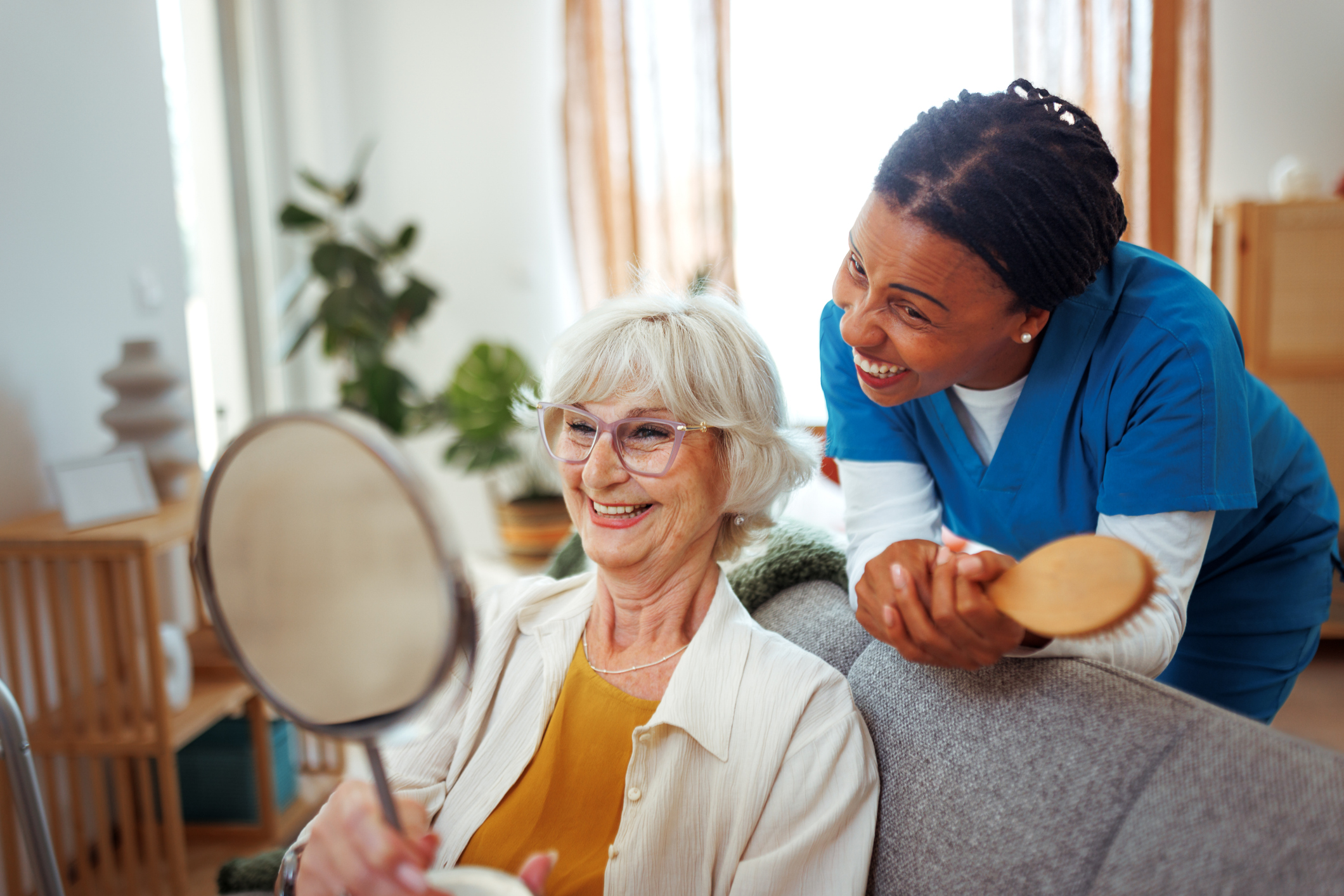 Female nurse helping senior woman with hair at home