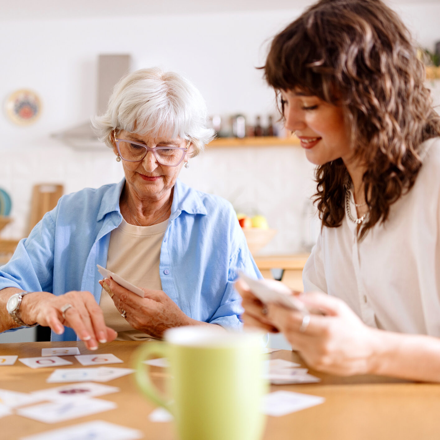 Senior woman and her granddaughter playing cards at home